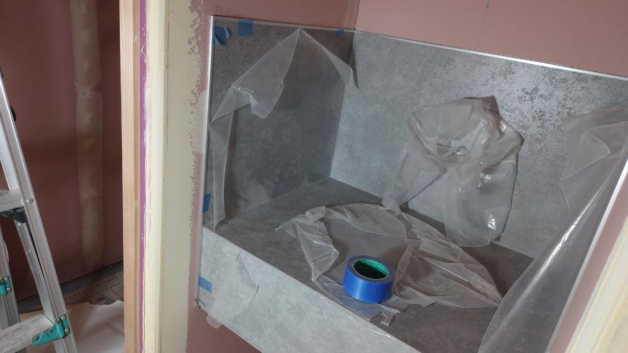 トイレ前手洗い部分の化粧パネル貼りが行われています。図面を確認し、正しい位置に取り付けられています。