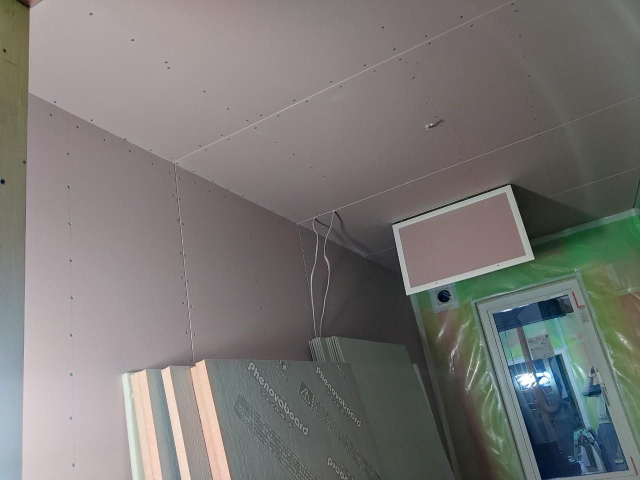 壁のボード貼りが行われている様子です。図面を確認し、正確に施工を進めております。