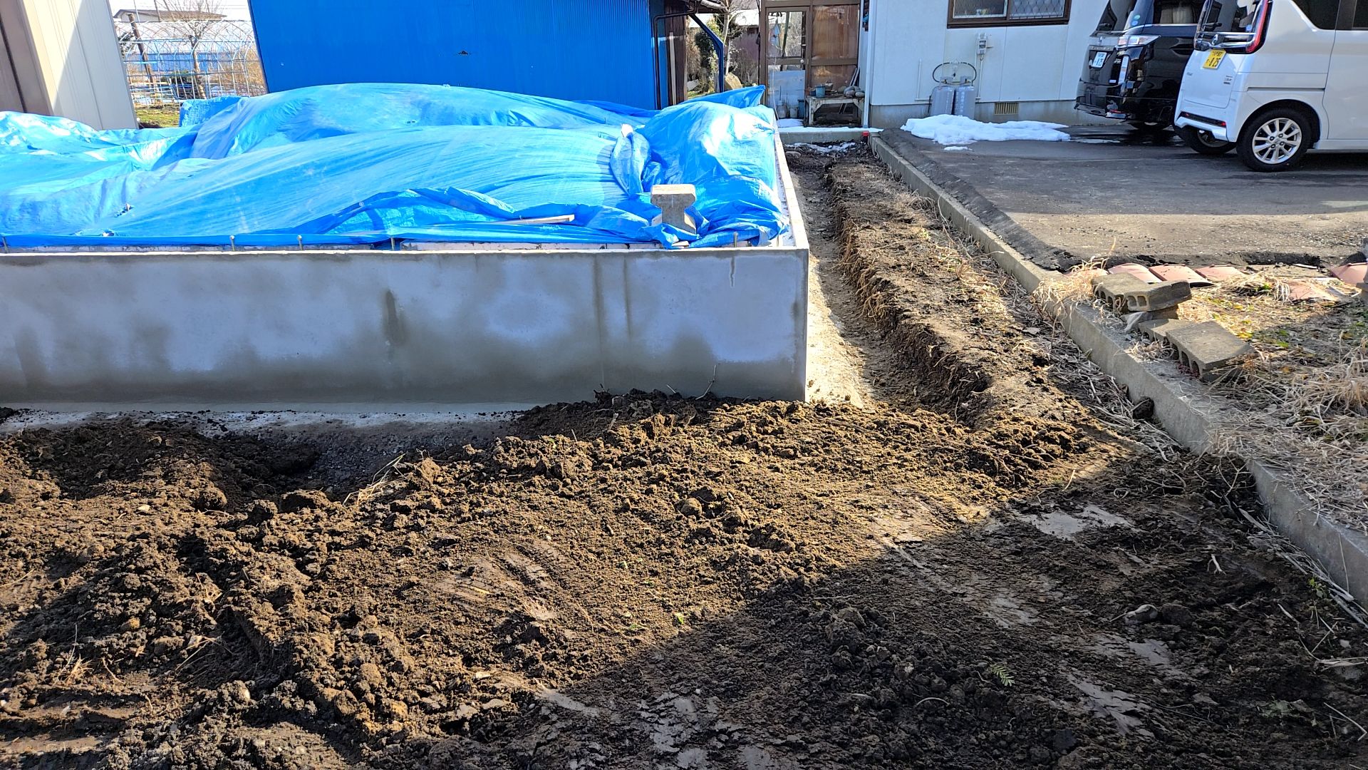 養生シートが飛ばされないよう注意しながら作業を進めています。