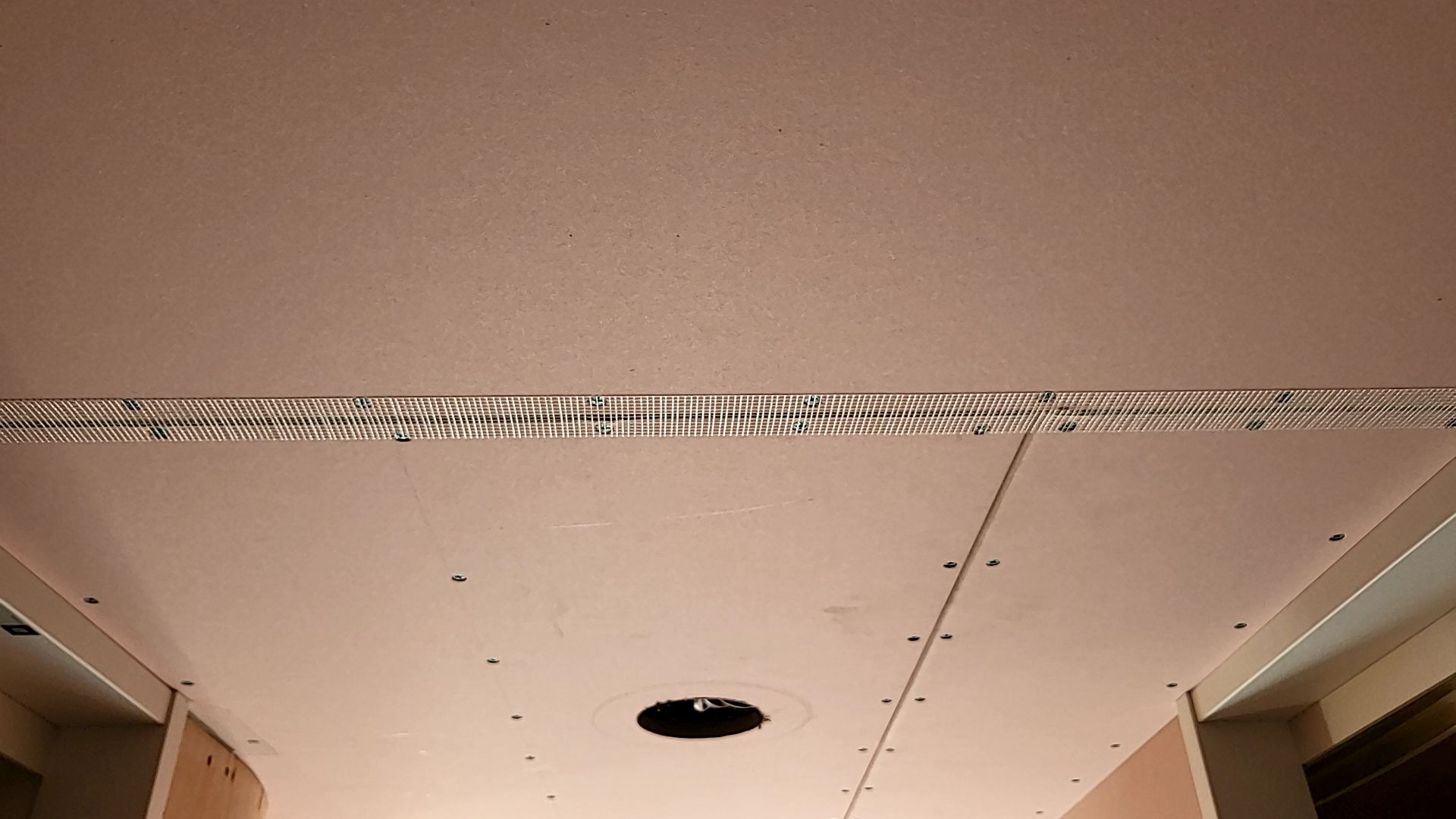 クロス工事が始まりました。継目が分からないように、ボードのジョイント部分に丁寧にテープをはっている様子です。